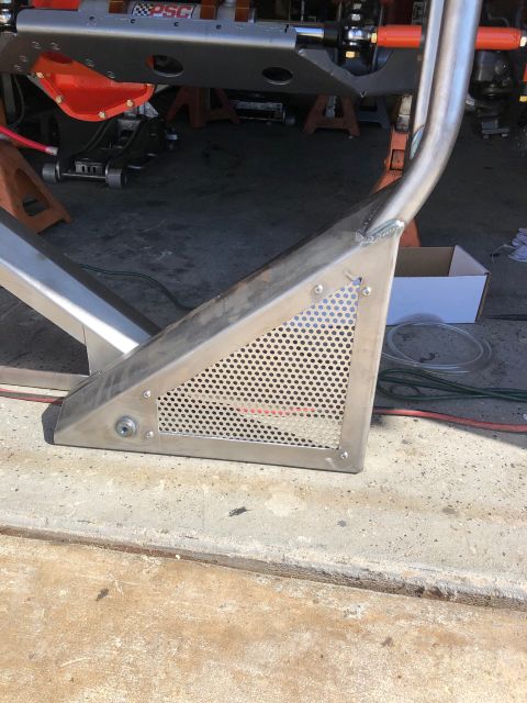 1992 Jeep Wrangler - A close-up view of a custom-fabricated stainless steel skid plate with a perforated section, attached to a vehicle frame supported by jack…