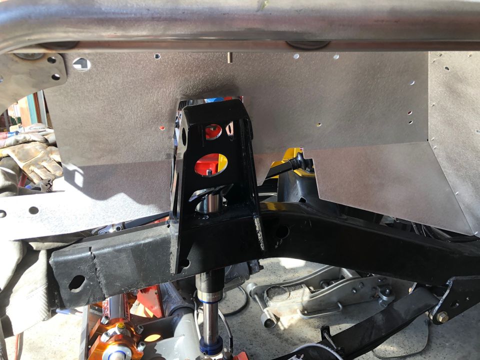 Close-up of a custom black metal frame attached to a silver panel on a vehicle chassis.