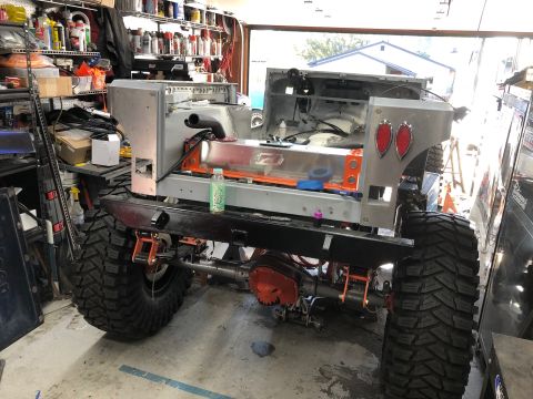 1992 Jeep Wrangler - The rear chassis and suspension of a custom off-road vehicle are shown in a garage setting. The vehicle features large, aggressive tires an…