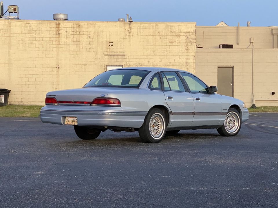 Light blue 1994 Ford Crown Victoria, rear passenger side view, chrome wire wheels, aftermarket wheels