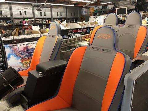 1992 Jeep Wrangler - Two custom PRP racing seats with orange and gray upholstery are installed in what appears to be a vehicle under construction. A black cente…
