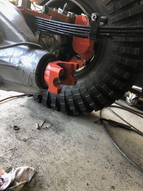 1992 Jeep Wrangler - A close-up view of the rear axle assembly of a vehicle, showing a bright orange differential yoke and red brake calipers. The leaf springs…