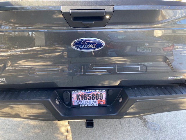 Rear view of a dark gray Ford F-150 pickup truck with license plate K165809.