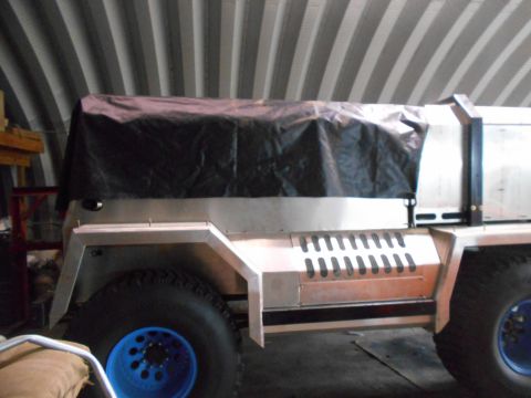 1992 Ford Bronco - A custom-built aluminum truck bed cover is shown on a vehicle with large off-road tires and blue rims. The vehicle is parked inside a build…