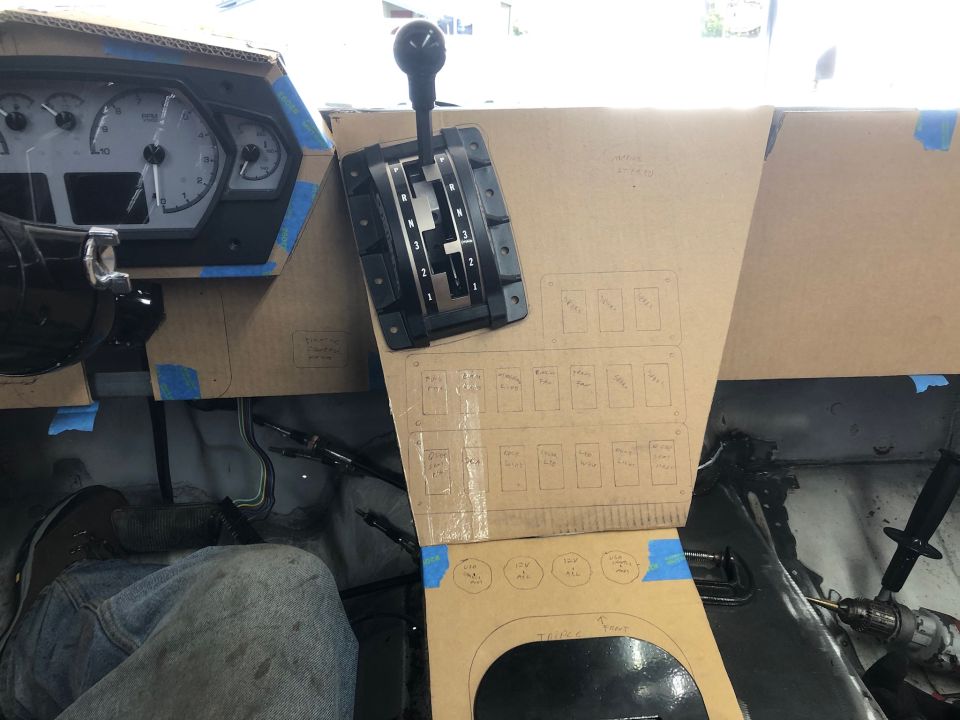Cardboard dashboard mockup with gear shifter and switch panel outlines in a vehicle.