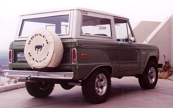 Green Ford Bronco with white top and 'Bronco Ranger' spare tire cover, rear 3/4 view