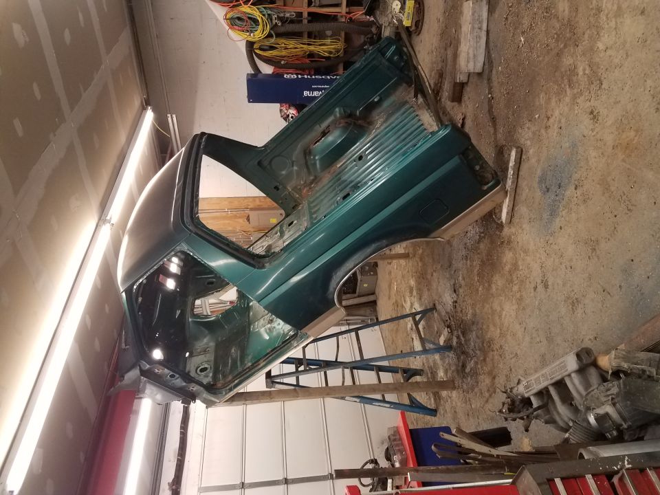 Green 1994 Ford Bronco body in a workshop, undergoing restoration.