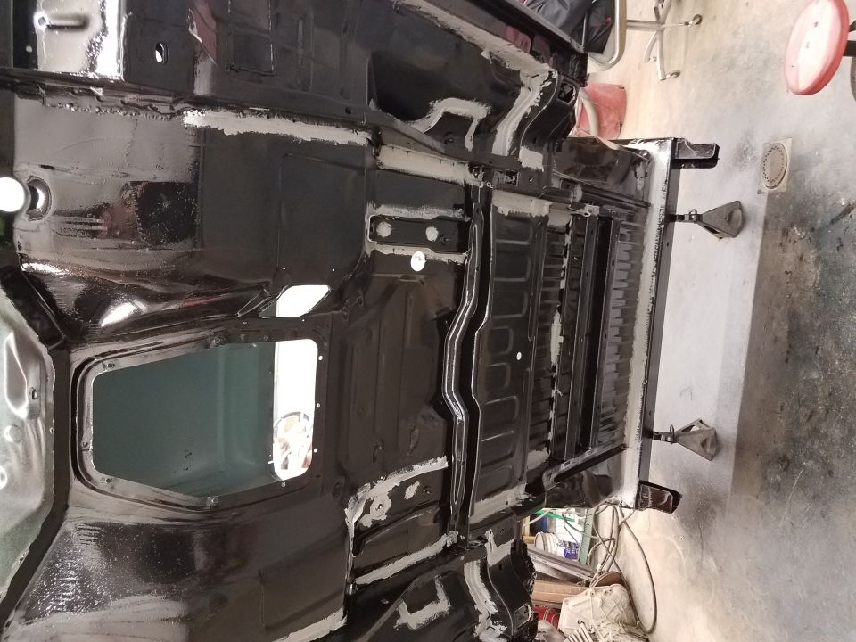Underside of a vehicle chassis, painted black with white sealant.