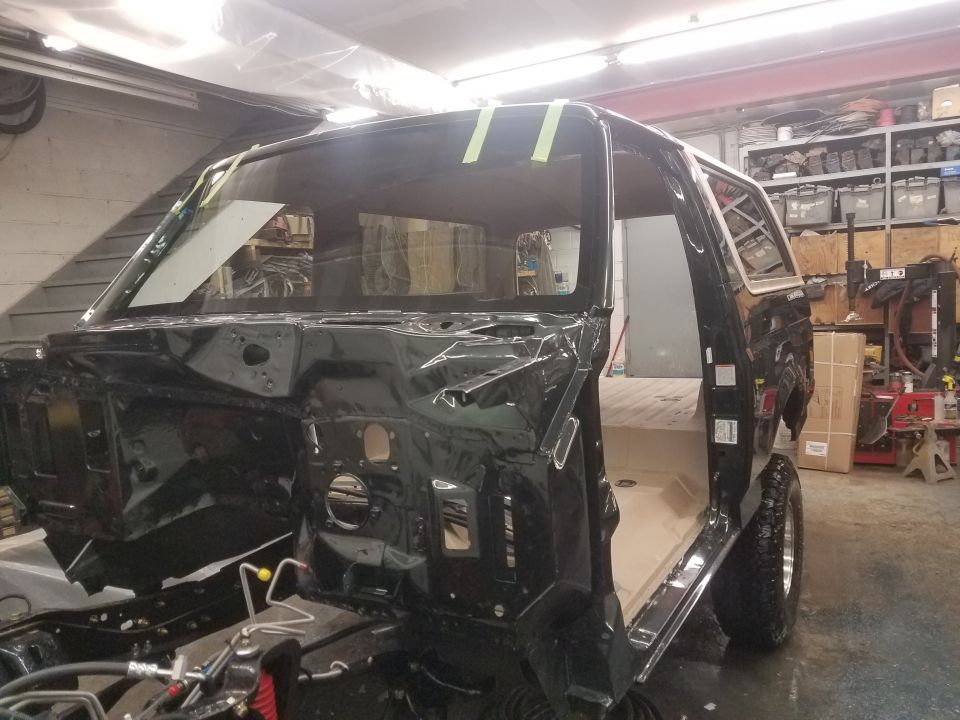 Black Ford Bronco undergoing restoration in a workshop, front 3/4 view.