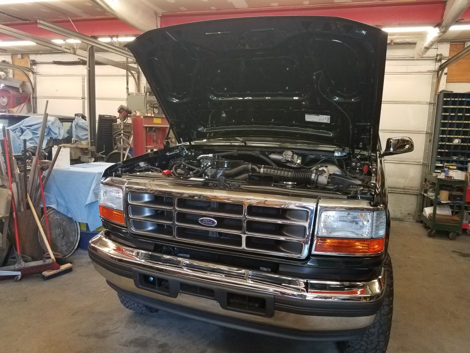 1994 Ford Bronco with hood open, front view, in a garage.