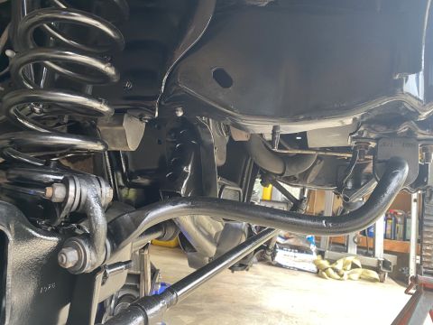 1994 Ford Bronco - The underside of a vehicle's suspension system, featuring black painted components including the sway bar, springs, and frame.