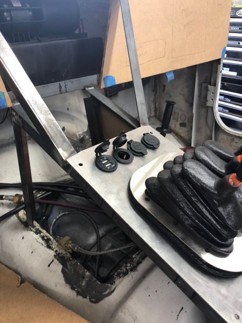 1992 Jeep Wrangler - A custom metal console with multiple USB and 12V power outlets is installed in a vehicle, along with a black shifter boot. The surrounding…