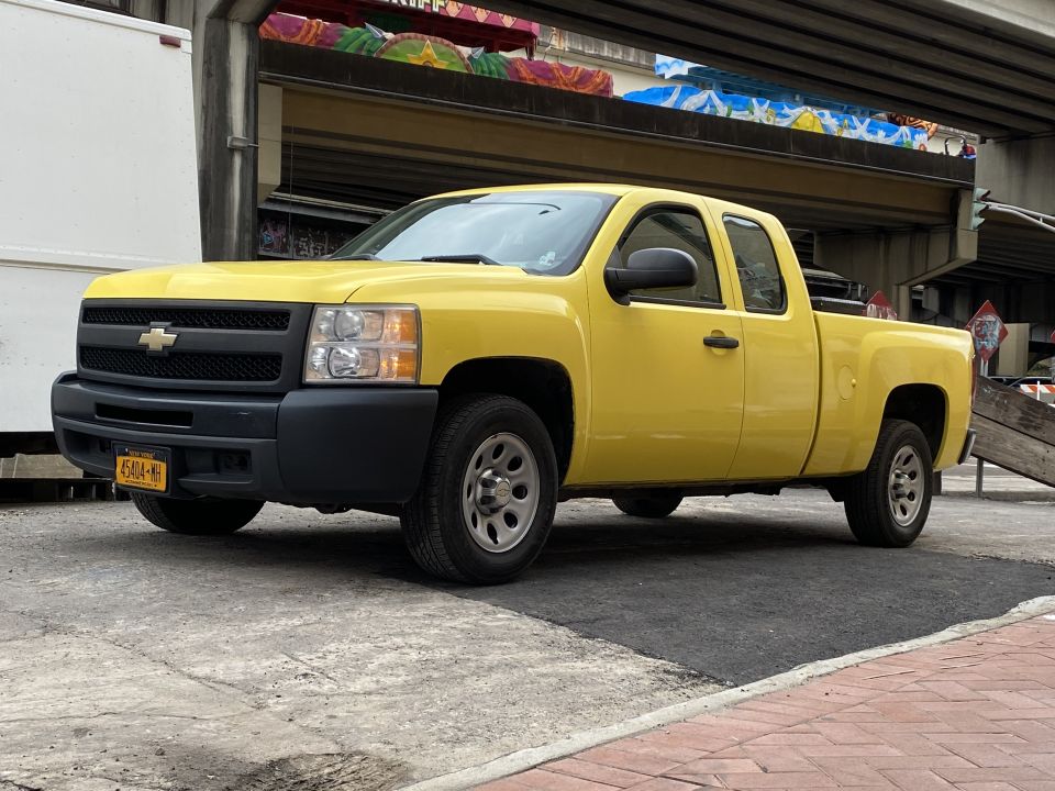 Yellow 2011 Chevrolet Silverado 1500 pickup truck parked on a street.