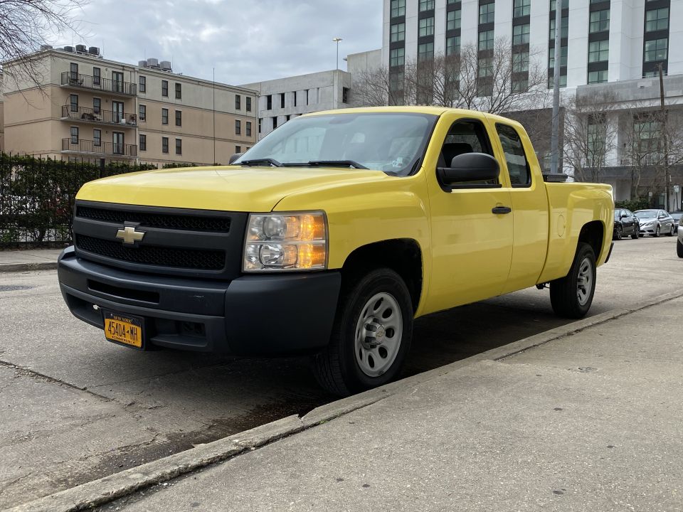 Yellow Chevrolet Silverado pickup truck parked on a city street, front three-quarter view.