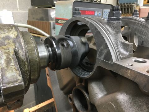 1979 Ford Bronco - A close-up view of a crankshaft being machined inside a dark gray engine block. The machining tool is actively cutting into the bearing jou…