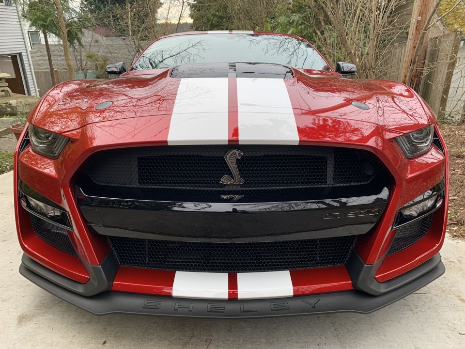 Red 2020 Ford Mustang Shelby GT500 with white racing stripes, front view.