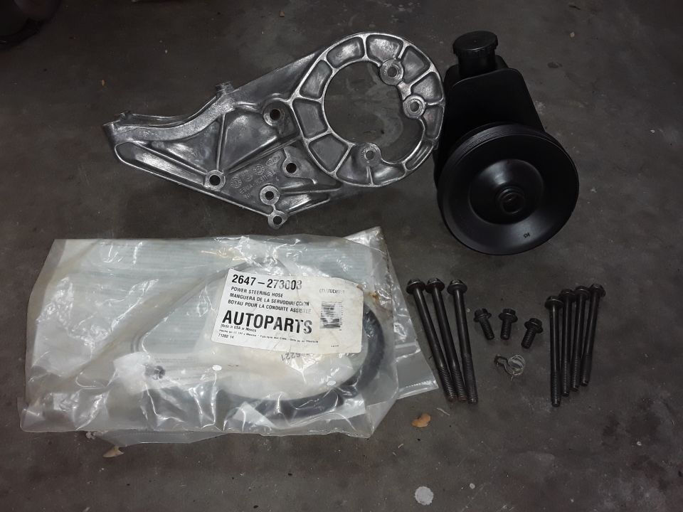 New Ford Bronco power steering pump, bracket, hose, and bolts on concrete.