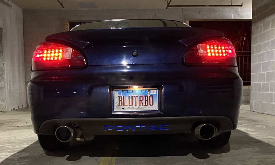 Rear view of a dark blue Pontiac Grand Prix with a custom license plate.