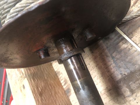 1980 Ford Bronco - A close-up view of a heavily greased metal shaft and a rusty, circular metal plate with three protruding pegs. A thick rope is wrapped arou…