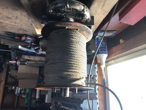 1980 Ford Bronco - A large spool of cable is mounted overhead, with various tools and a bottle of lubricant visible in the background.