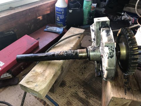 1980 Ford Bronco - A close-up view shows a heavily greased metal shaft and gear assembly resting on wooden blocks, with tools and cleaning supplies visible in…
