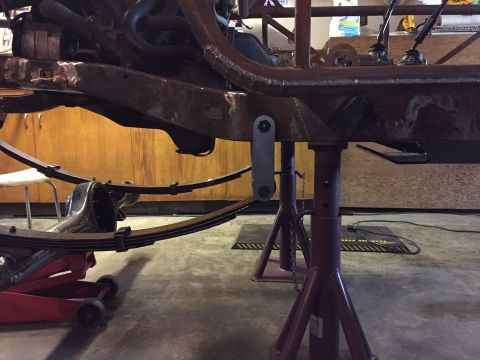 1985 Toyota Hilux - Close-up of a truck's frame and suspension system, supported by jack stands in a workshop.