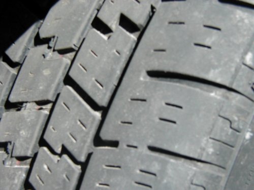 Close-up of a tire tread with visible wear and a Supermotors.net logo