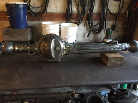 1985 Toyota Hilux - A rear axle assembly is shown, resting on blocks on a workbench. The differential housing is visible in the center.