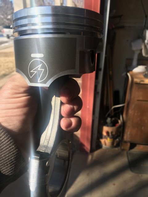 2000 Ford Explorer - Piston and connecting rod assembly held in hand, showing a lightning bolt logo on the piston.