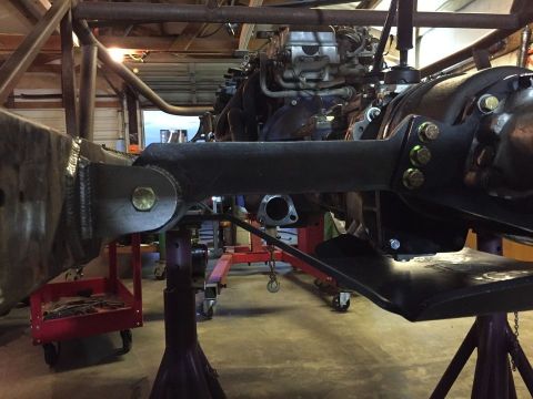 1985 Toyota Hilux - Close-up view of a vehicle's engine and drivetrain components, supported by jack stands in a workshop.