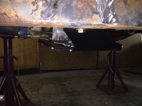 1985 Toyota Hilux - The underside of a vehicle is shown, focusing on the transmission and frame components, elevated on jack stands.