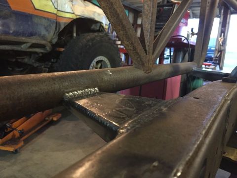1985 Toyota Hilux - Close-up of a vehicle's welded frame, with a large tire and a colorful vehicle visible in the background.