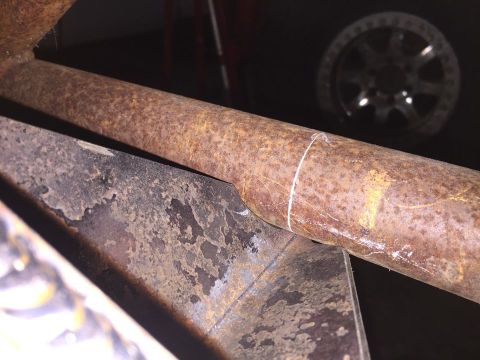 1985 Toyota Hilux - Rusted metal pipe and bracket detail, with a wheel visible in the background.