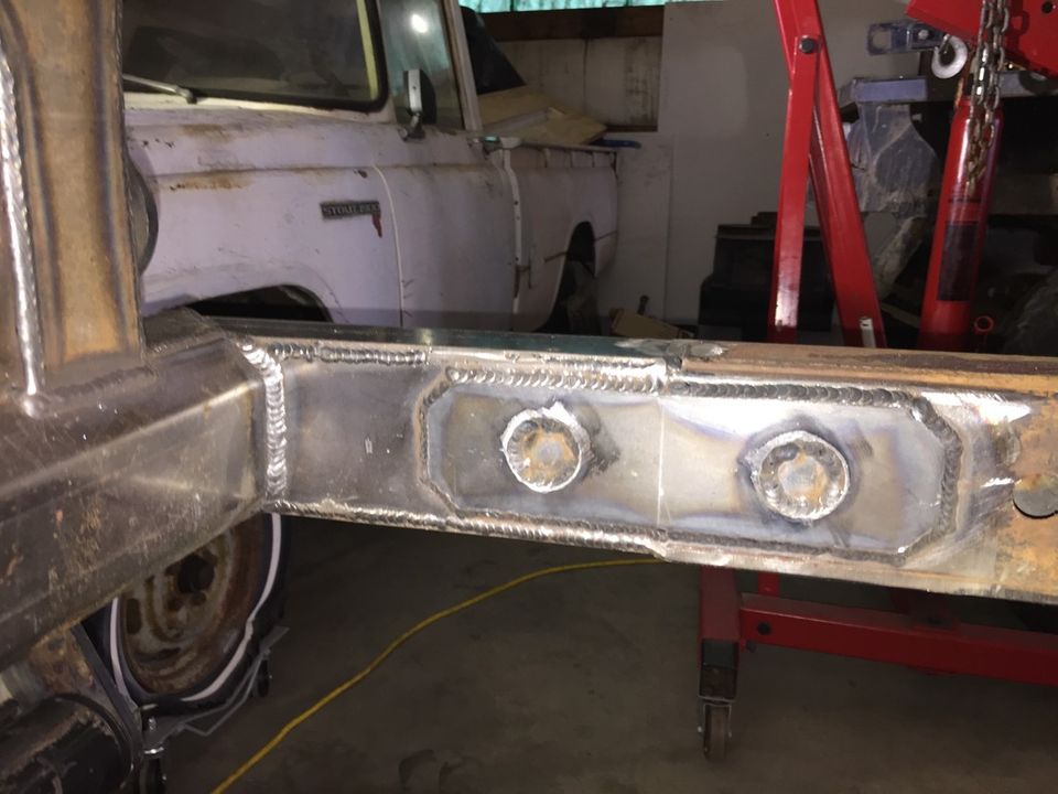 Welded frame section of a truck, with a white truck in the background
