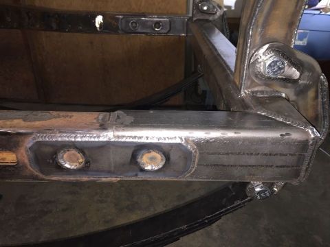 1985 Toyota Hilux - Close-up of a welded metal frame with bolts and leaf springs, likely part of a vehicle's suspension system.