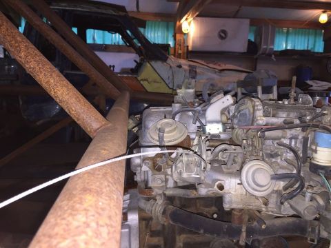 1985 Toyota Hilux - A close-up view of a dirty, rusty engine, likely from a 1985 Toyota Hilux, with various hoses, carburetor components, and a vacuum booster…