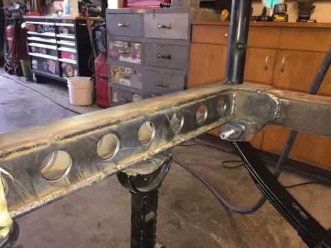 1985 Toyota Hilux - A close-up view of a custom-fabricated steel frame section with multiple circular cutouts, supported by jack stands in a workshop setting.…