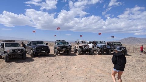 1992 Jeep Wrangler - A group of off-road vehicles are parked on a dusty trail under a partly cloudy sky.