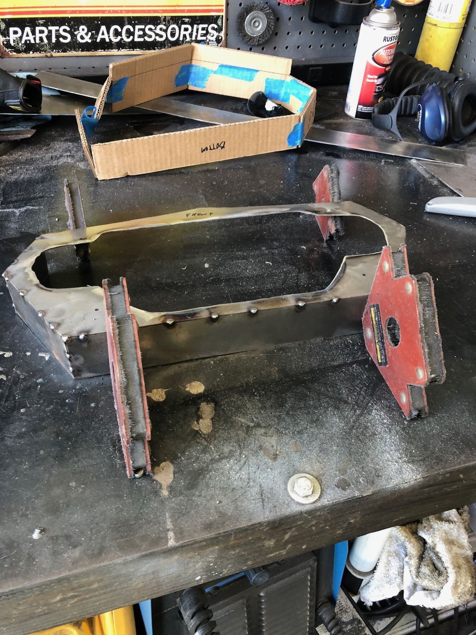 Metal frame being worked on a workbench with tools and a cardboard template
