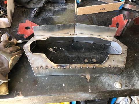 1992 Jeep Wrangler - Welded fabricated sheet-metal box panel hand-marked FRONT, held by red magnetic clamps on a workbench with welding gloves.