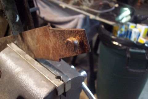 1995 Ford Bronco - Close-up of a rusted metal bracket secured in a vise, likely for repair or fabrication.