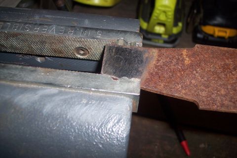 1995 Ford Bronco - A close-up view of a rusty metal component secured within a vise.