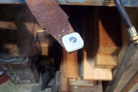 1995 Ford Bronco - Close-up of a rusty metal bracket with a white plastic cap and visible bolt, part of an unknown mechanism.