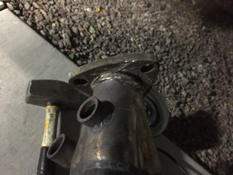 1993 Mercury Tracer - Close-up view of a welded exhaust pipe flange with threaded fittings, alongside a hammer.
