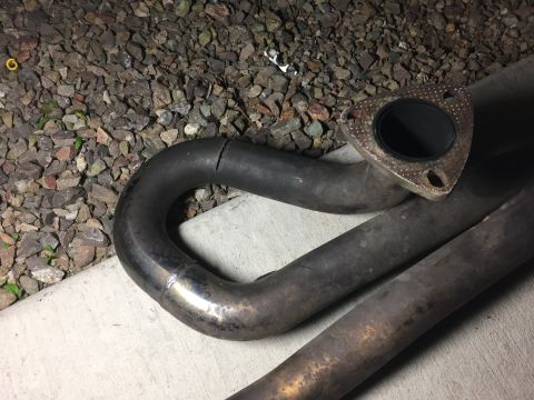 1993 Mercury Tracer - A cracked exhaust pipe is shown resting on gravel and concrete. The flange is visible at the top right.