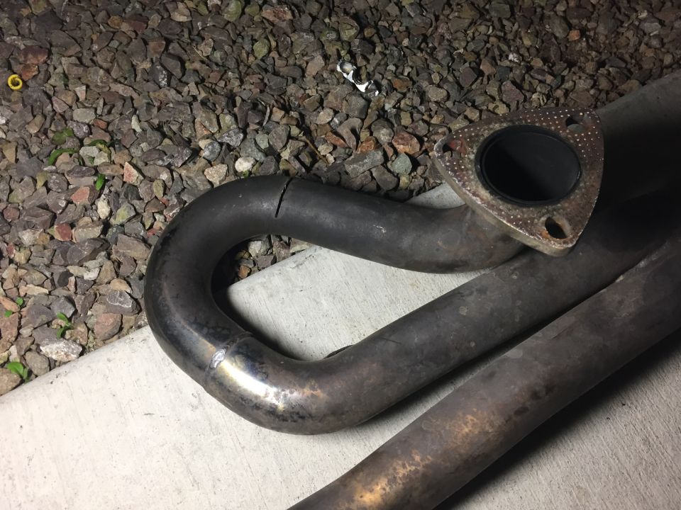 Cracked exhaust pipe with a flange. Text at bottom says SUPERMOTORS.NET
