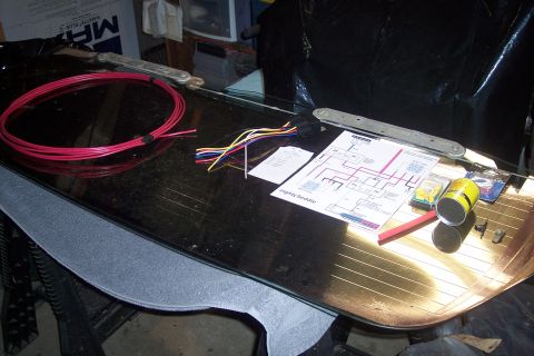 1995 Ford Bronco - A wiring diagram and various electrical components are spread out on a surface, possibly for a vehicle repair or installation.