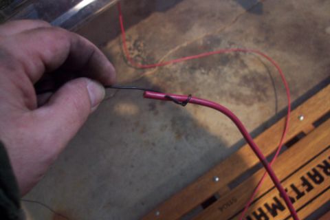1995 Ford Bronco - A hand is shown connecting two wires, one red and one black, using a crimp connector.