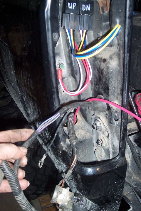 1995 Ford Bronco - A hand is shown working on a complex vehicle wiring harness with multiple colored wires.