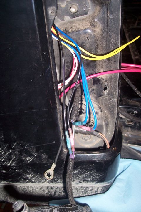 1995 Ford Bronco - A tangle of wires and connectors are visible behind a vehicle's body panel.